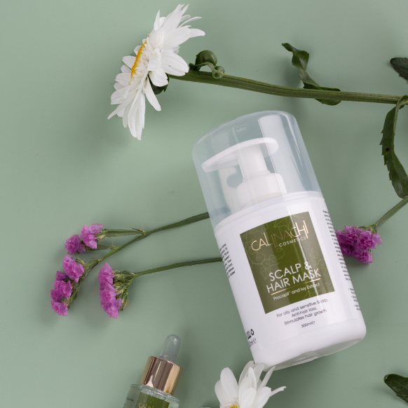 Hair care products with flowers on a green background